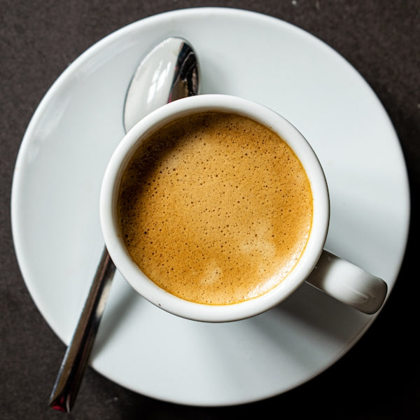 a cup of coffee on a saucer with a spoon
