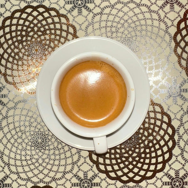 Here's a caption: espresso coffee in a white cup.