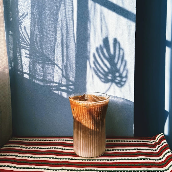 Iced coffee with plant shadow on wall