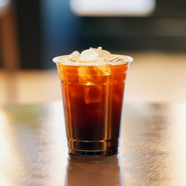 Iced coffee in a clear cup on a wooden table.