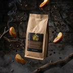 Brown coffee bag with a label on a dark background with coffee beans and apples.