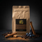 Brown coffee bag with cinnamon, blueberries, and coffee beans on a dark background
