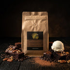Brown paper bag with coffee label, brownies, ice cream, and coffee beans on a dark surface